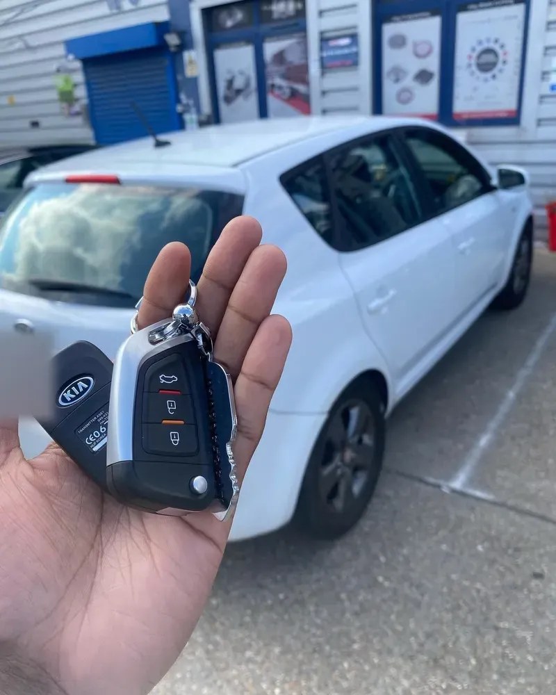 Replacement Kia smart key held in front of the car it was coded for